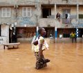 A woman with a baby on her back wades through water after overnight flooding on a street in Senegal's capital Dakar, August 14, 2012. REUTERS/Joe Penney (SENEGAL - Tags: ENVIRONMENT DISASTER) - RTR36U9J