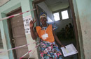 Член Независимой избирательной комиссии дает сигнал зайти в здание избирательного участка следующим двум избирателям для участия в выборах в Демократической Республике Конго.