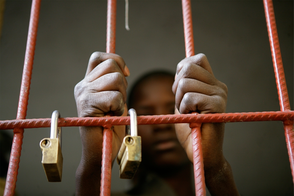 En 2009, au Mali, un garçon de 14 ans agrippe les barreaux de sa cellule à la prison pour mineurs de la ville de Mopti, dans la région de Mopti. L'UNICEF appuie un programme de justice pour mineurs et des ONG locales qui fournissent des services d'éducation et de regroupement familial à Mopti. Photo: UNICEF/ONUNY2009-1931/Pirozzi
