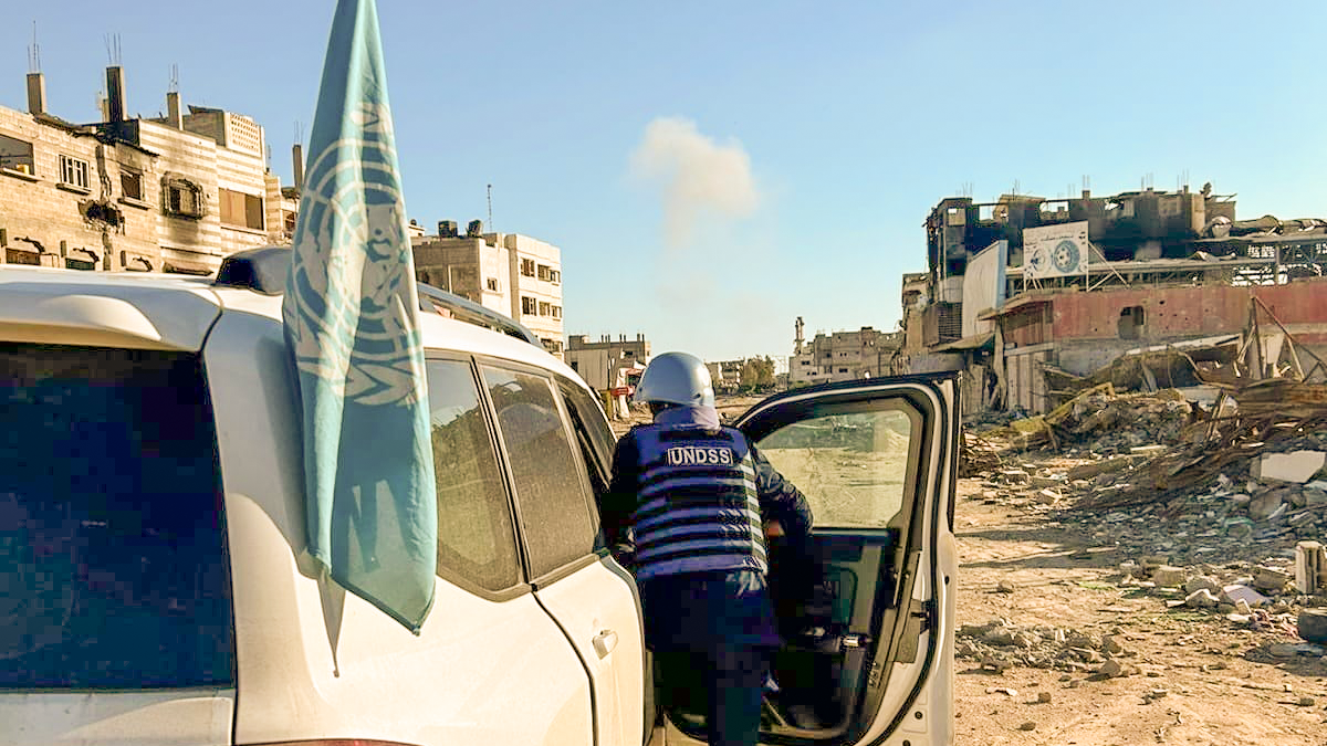 A man entering a vehicle in an area with damaged houses