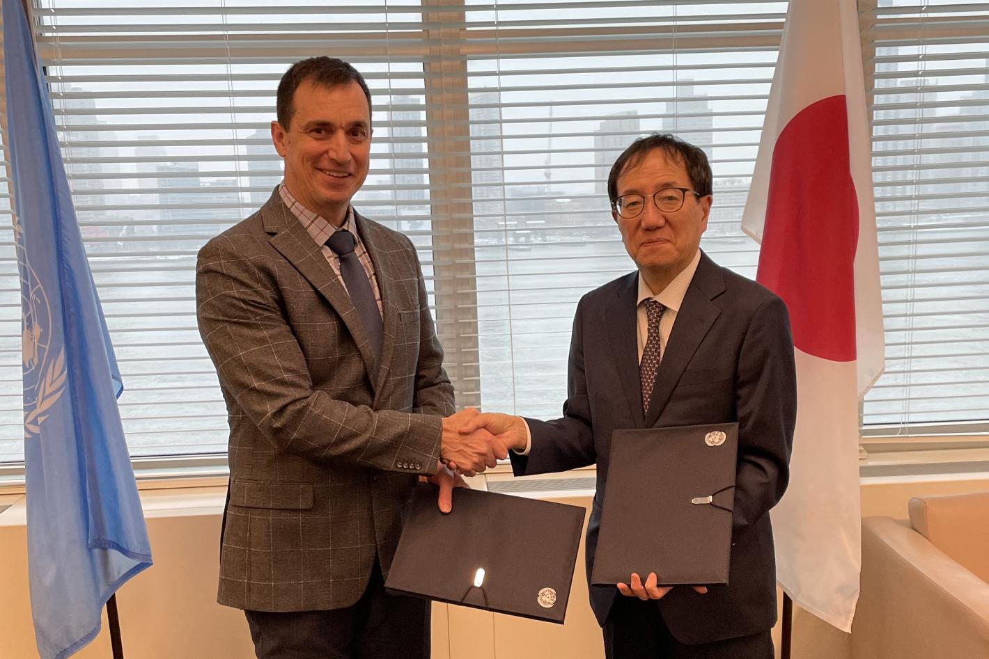 Two men shaking hands while displaying ceremonial documents