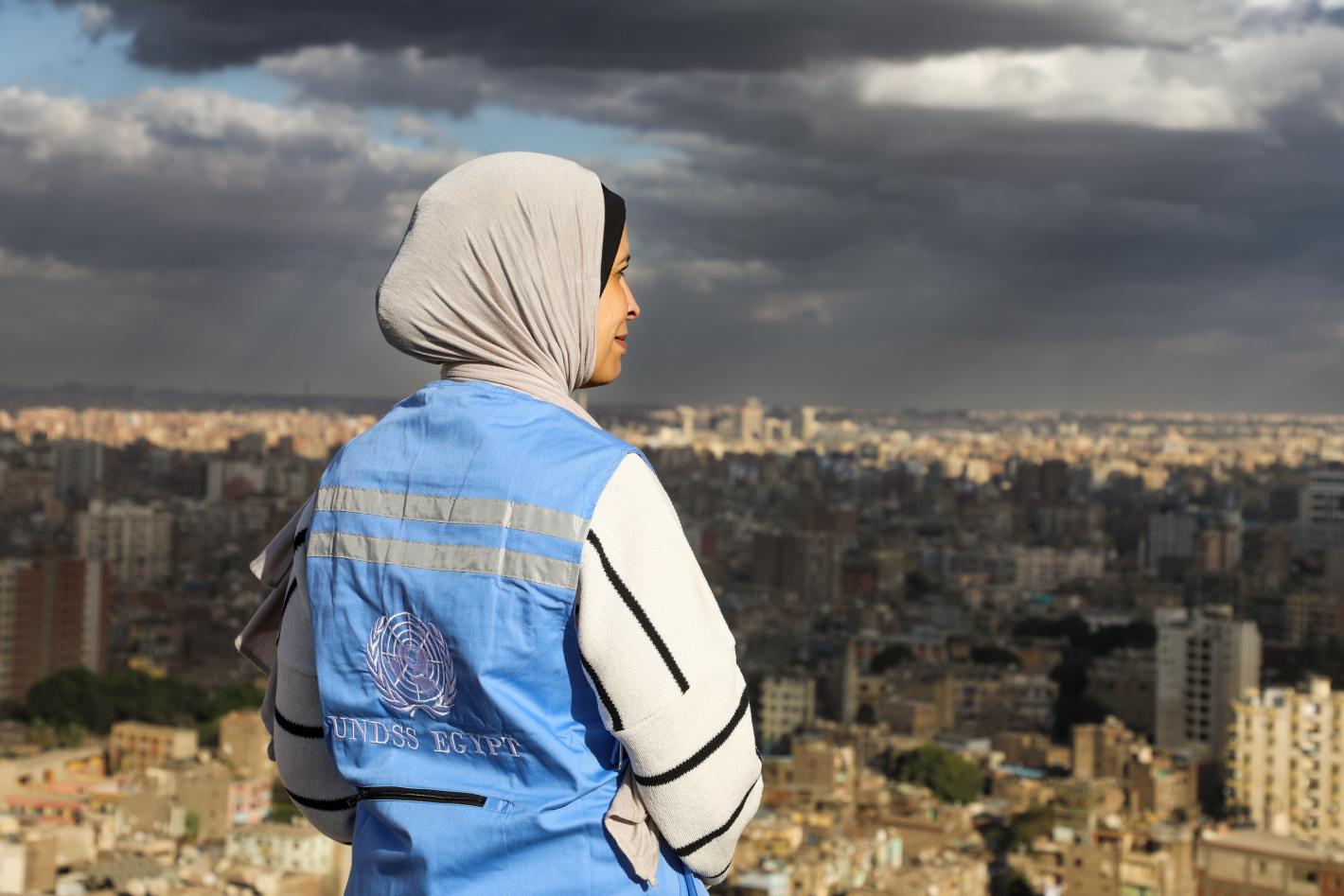 A woman wearing a head scarf overlooking a dense city
