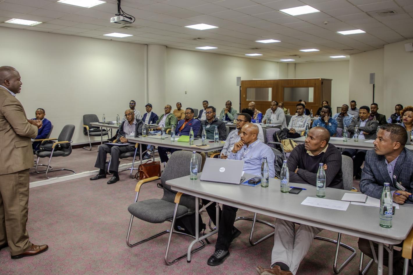 A man addressing a group of people sitted in a meeting room