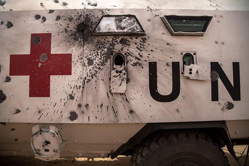 A white truck with a red cross damaged by bullet holes