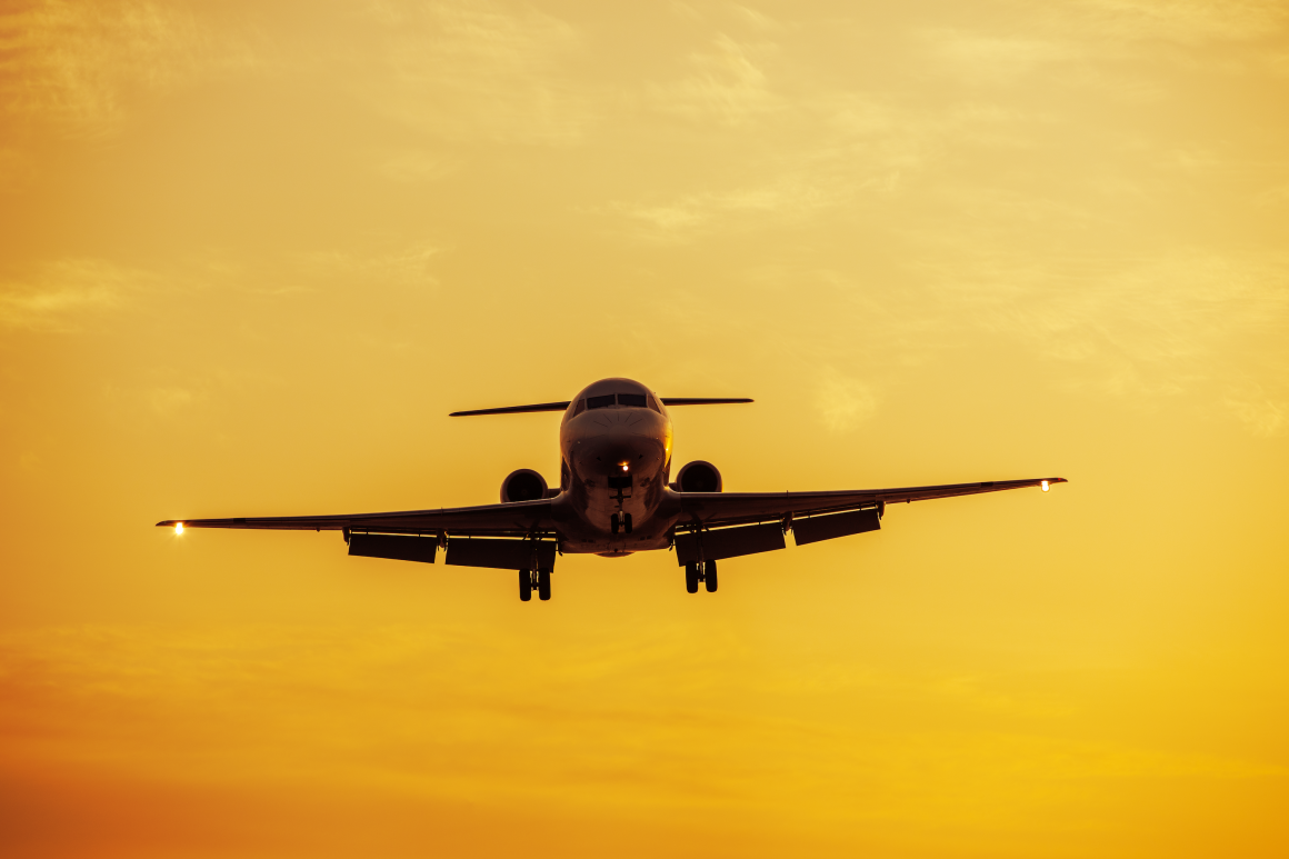 An aeroplane flying at low attitude at sunset