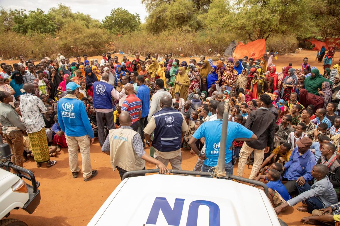 UN personnel in a remote location surrounded by a group of people