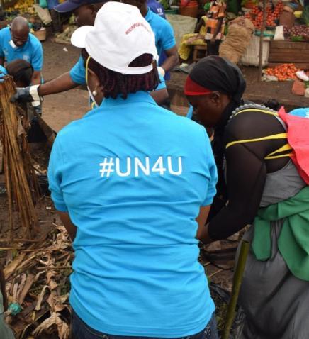 A woman wearing a branded t-shirt surrounded by people