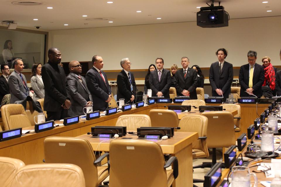 Committee members stand in observance of one minute of silence.