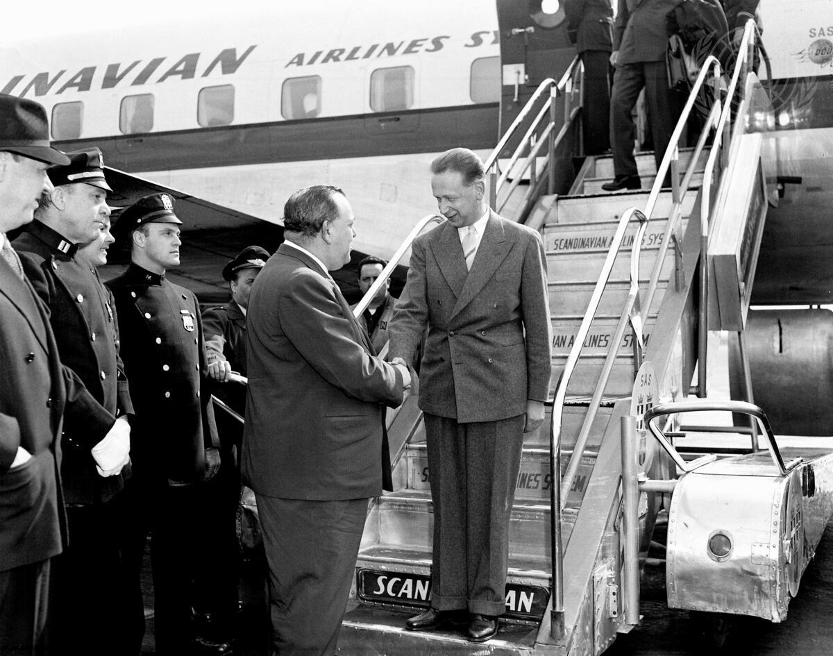 Dag Hammarskjöld shakes hands with Trygve Lie at the bottom of the stairs coming down the plane