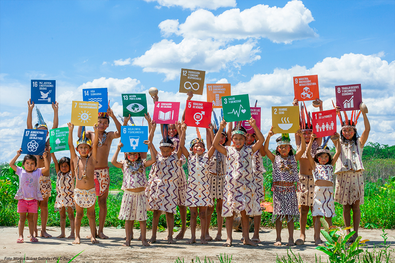Children wearing colorful clothes holding up cards with the 17 SDG goals.