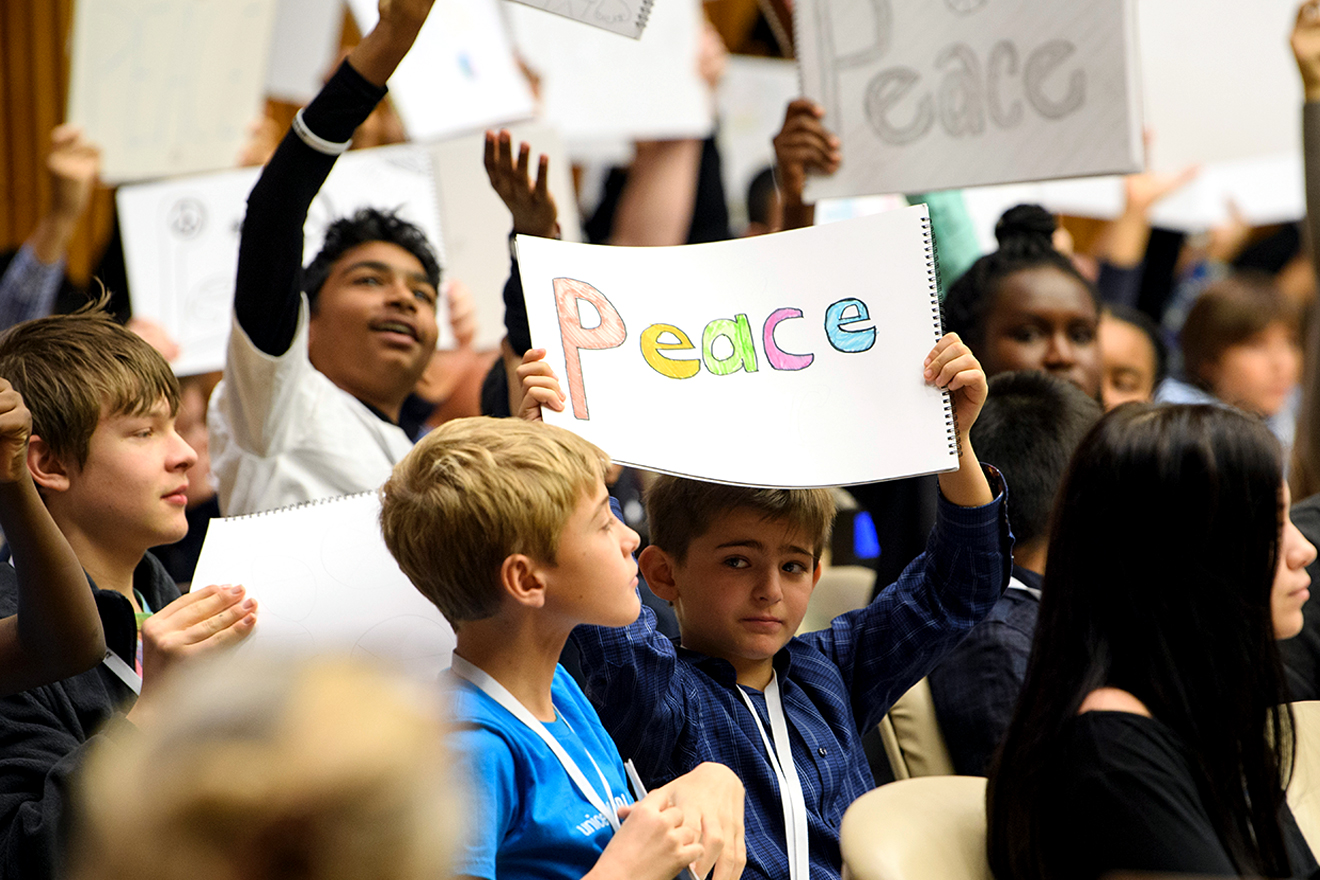 Children hold up signs that read “peace” in a UN Headquarters conference room in New York City.