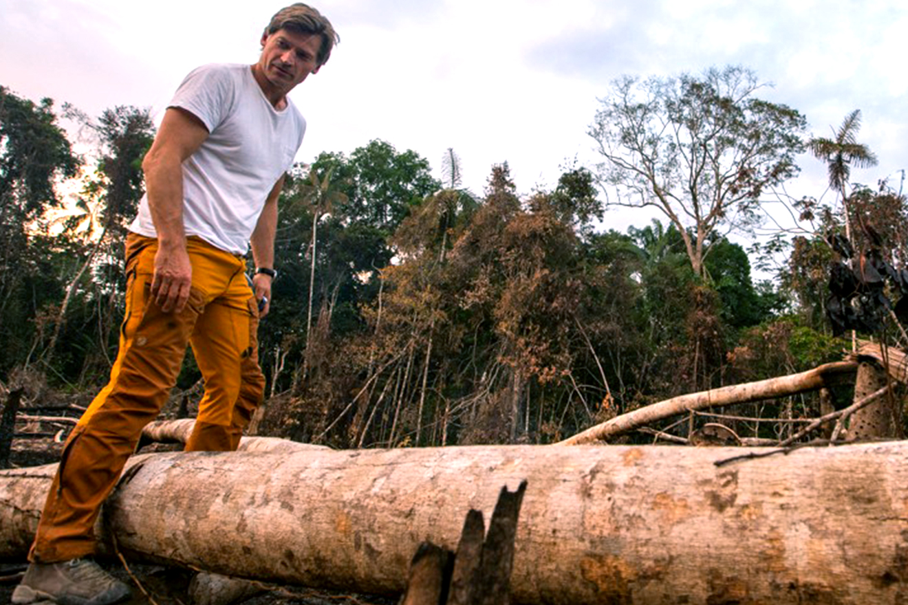 Photo of Game of Thrones star Nikolaj Coster-Waldau standing on fallen trees while he surveys the Amazon area affected by fires.