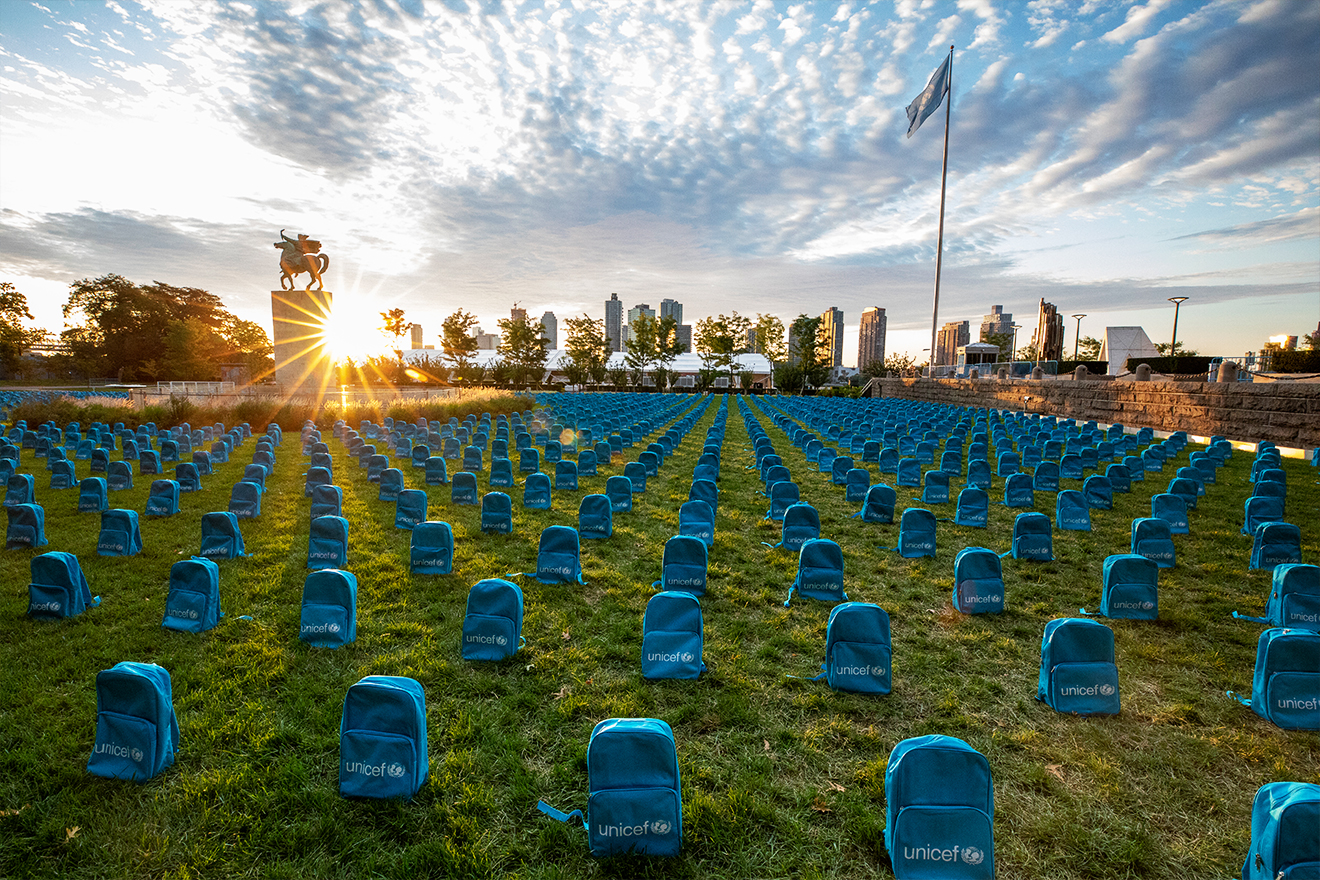 Rows of blue UNICEF backpacks arranged in the manner of a graveyard installed on the lawn at the UN in NY.
