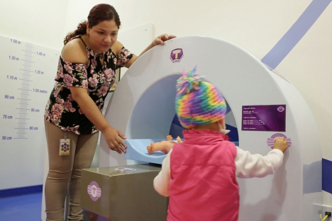 health care worker showing child an MRI machine