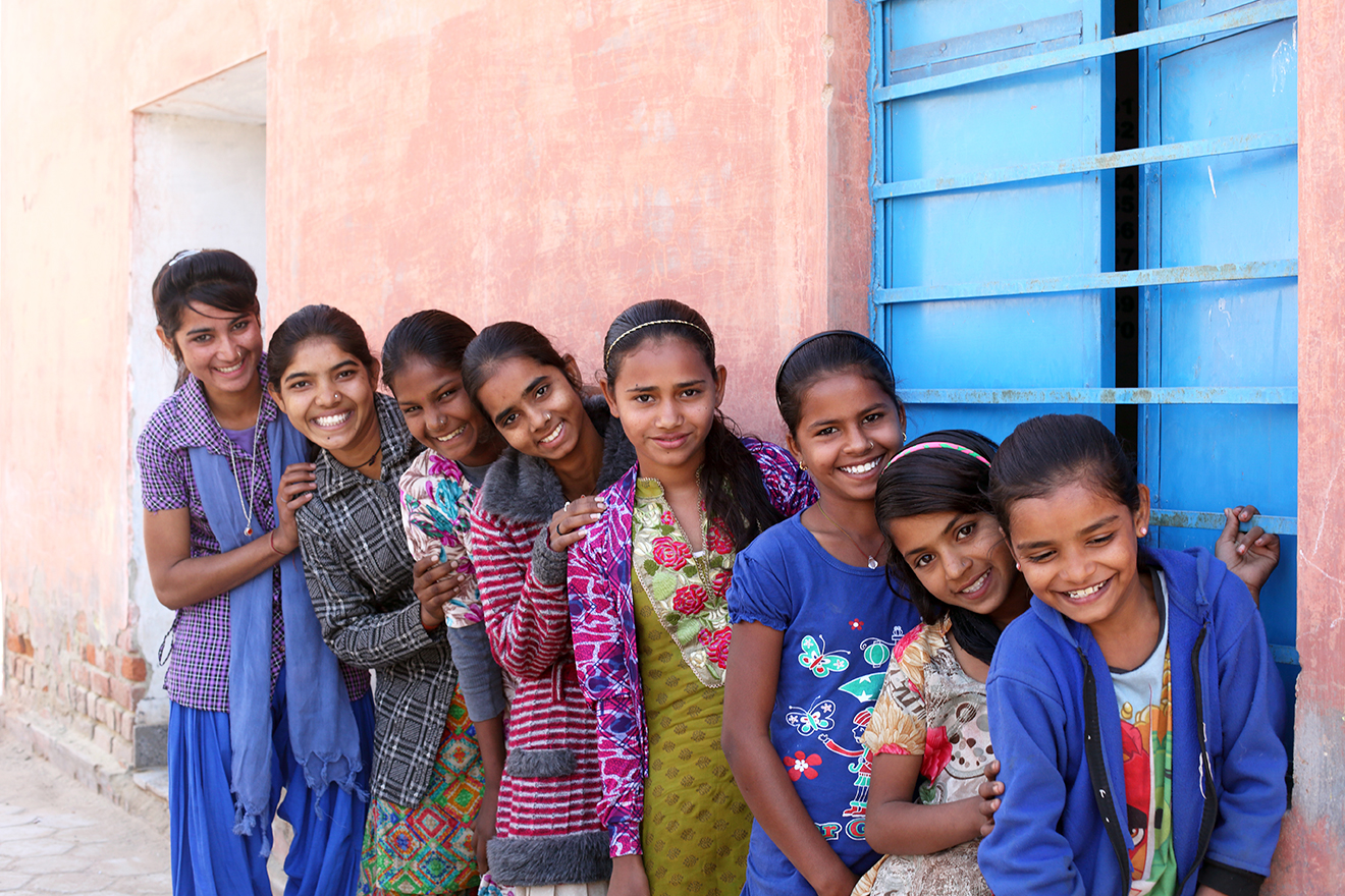 Young girls leaning against a pink wall, lining up from the shortest to the tallest for a photo-op.