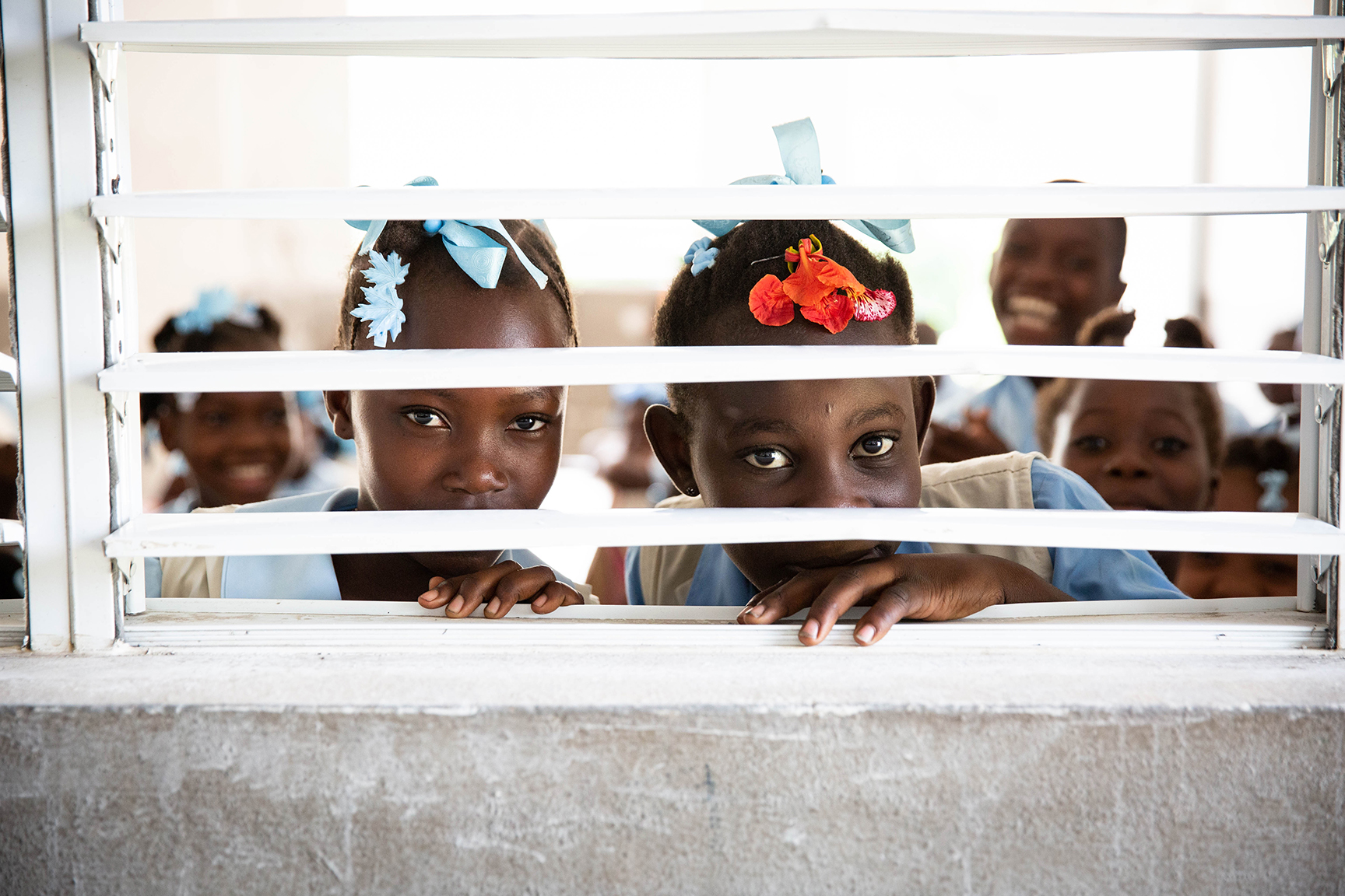 schoolchildren peek through window bars