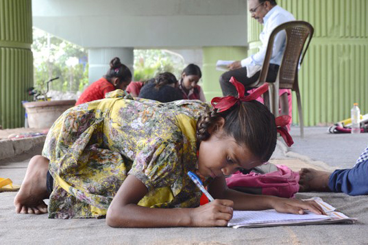 Une élève de primaire suit un cours d’hindi dans une école de fortune située sous un pont du métro aérien de New Delhi.