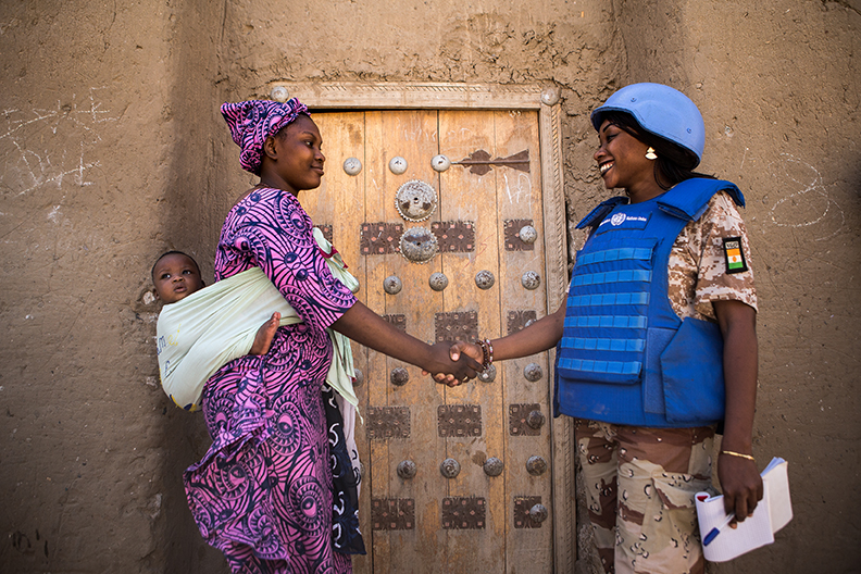 UN Police officer greets a woman and her baby