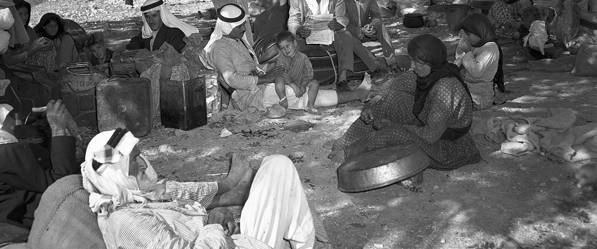 Un grupo de refugiados palestinos descansan en el suelo, esperando el transporte para proseguir su viaje, en 1948. 