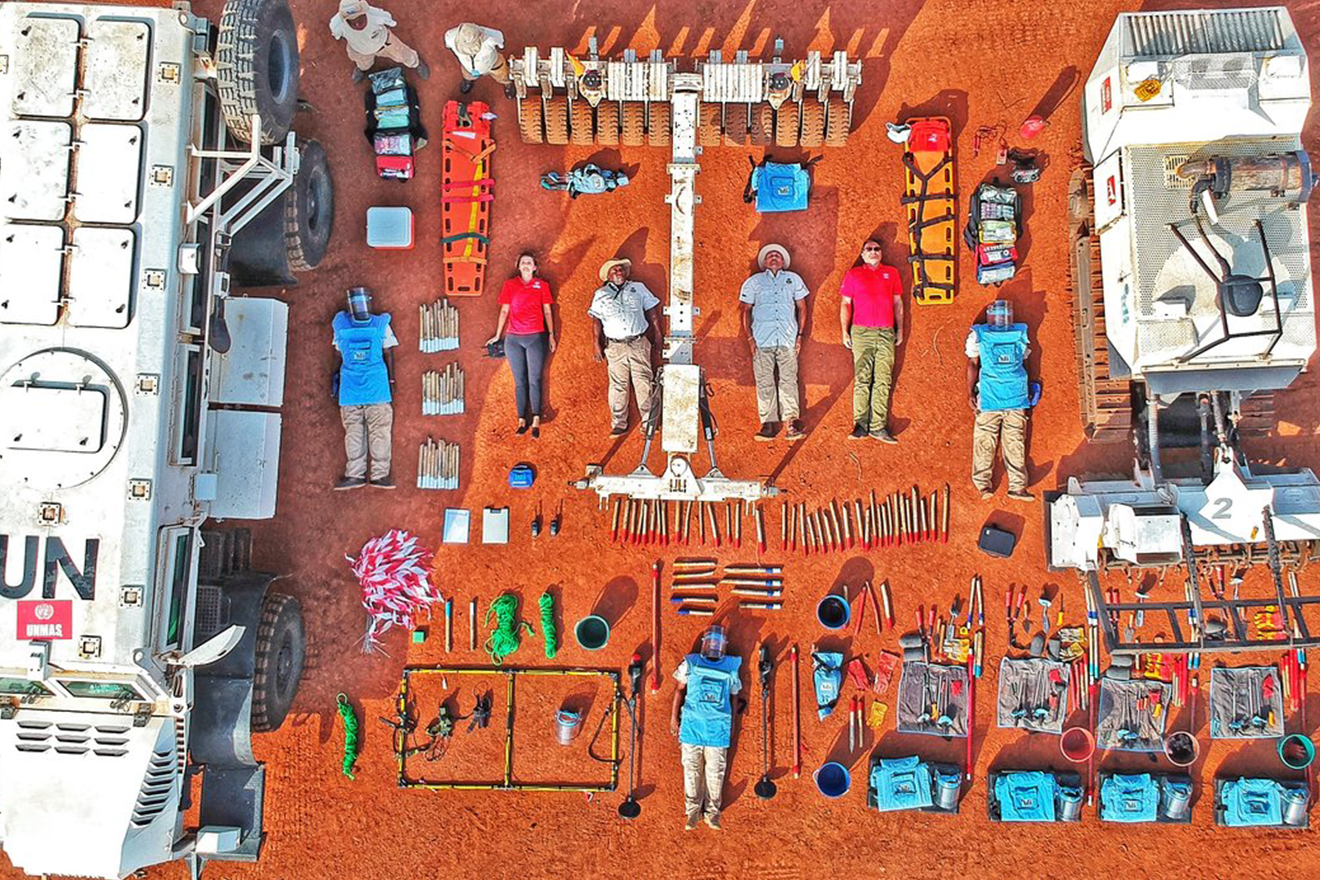 Staff and tools utilized in demining activities are laid down on the ground for an eye catching areal shot.