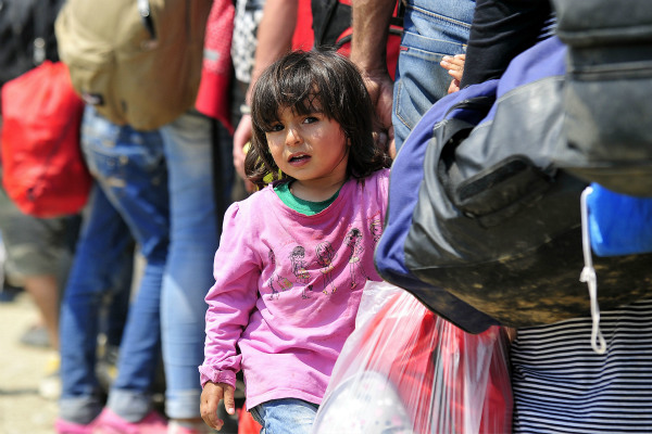  On 26 August, a young girl from the Syrian Arab Republic holds the hand of an adult while standing in a queue of people waiting to board a train to the border with Serbia, near the town of Gevgelija, on the border with Greece.