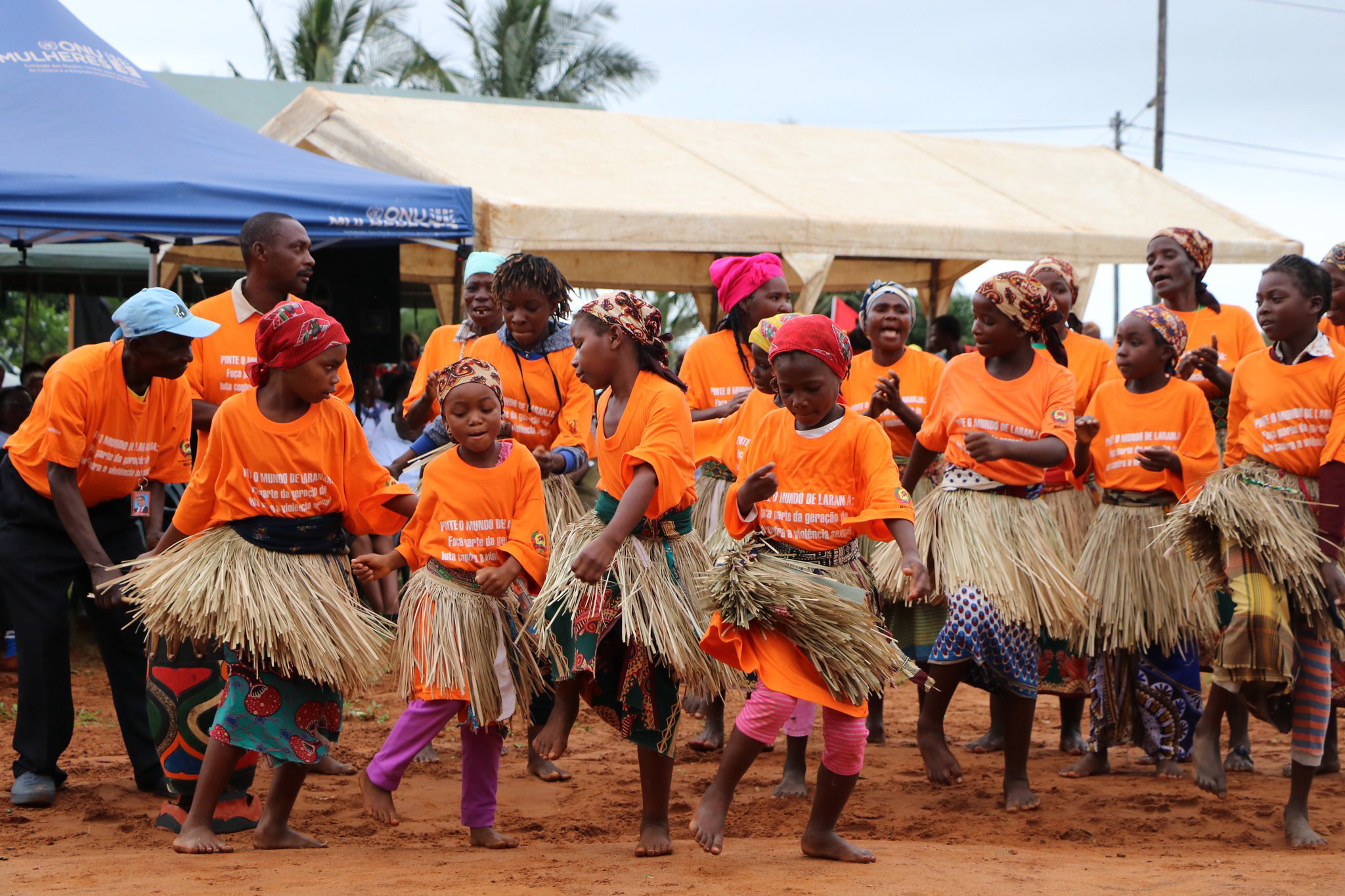 women and children in orange t-shirts perform