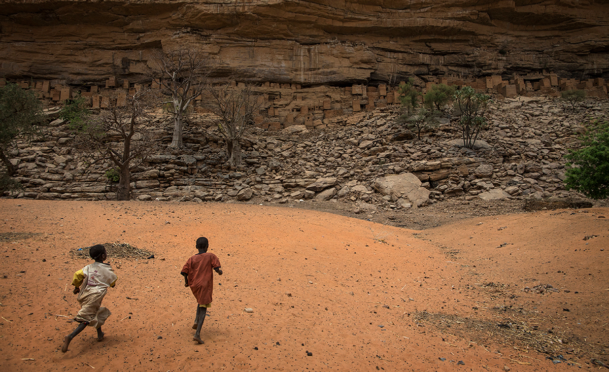 Children run towards cliff dwellings