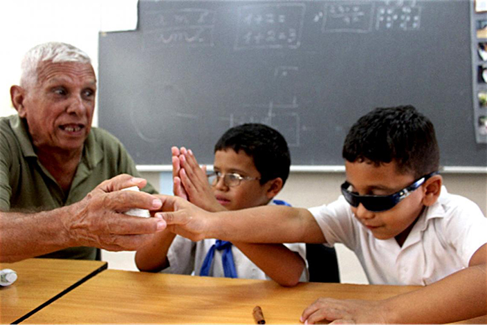 Professor Carlos Bartolomé interacts with vision-impaired students in a classroom.
