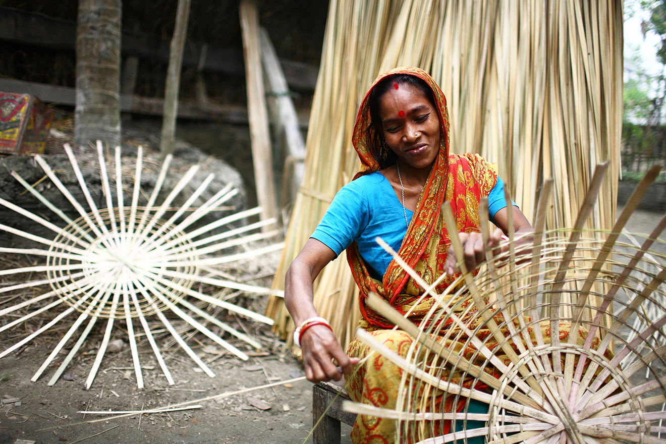 A woman weaves baskets out of bamboo sticks.