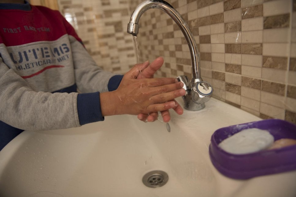 Photo of hands being washed over a sink with soap and water.