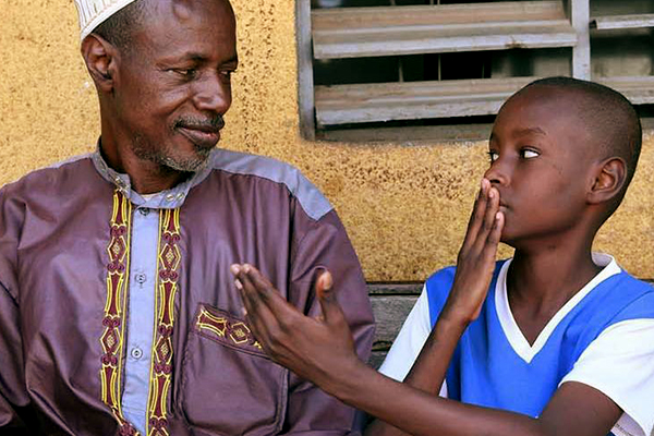 Child speaks in sign language with an adult.