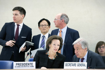 The president of the Human Rights Council exchanges a word with the Secretary-General while they are seated at a panel.