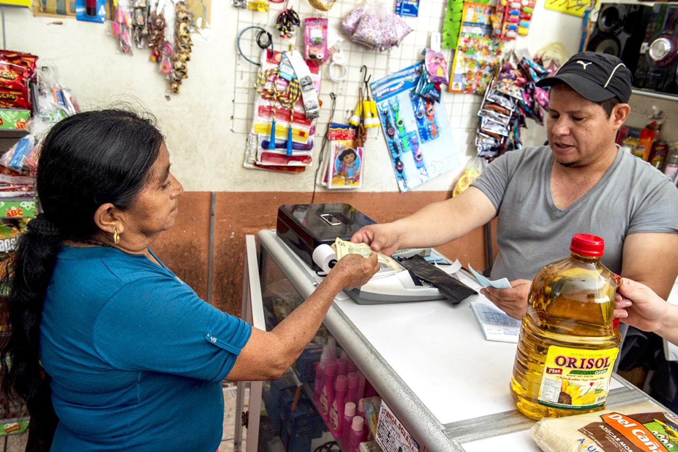 Money is exchanged between a teller at a convenience store and a customer
