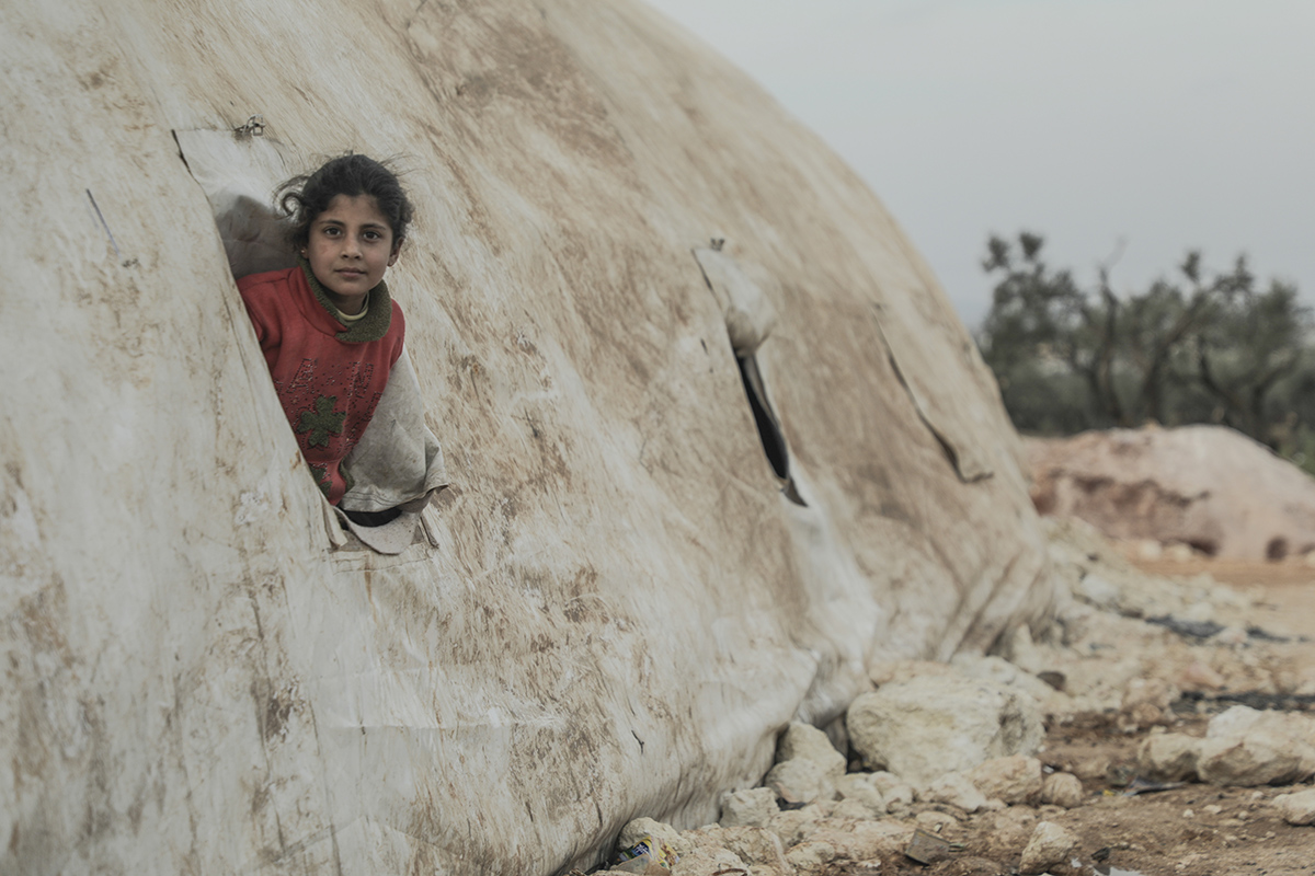 Syrian girl looks out from tent