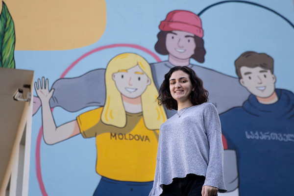 Girld stands in front of a mural