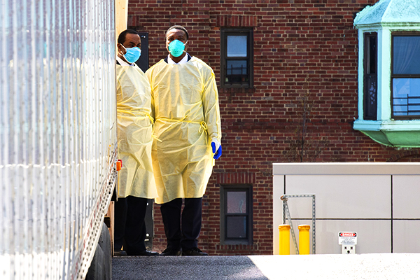 Two men wearing hospital protective gear.