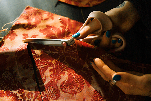 Hands with scissors cutting through cloth.