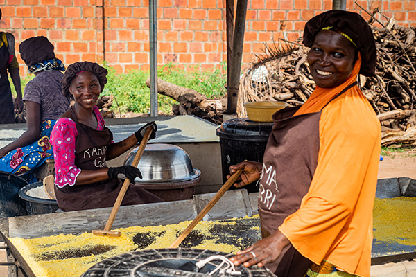 Women preparing food in an outdoor kitchen. 