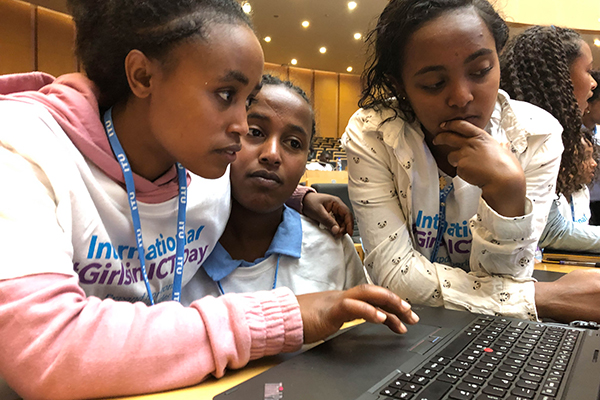 Three girls in front of a laptop.