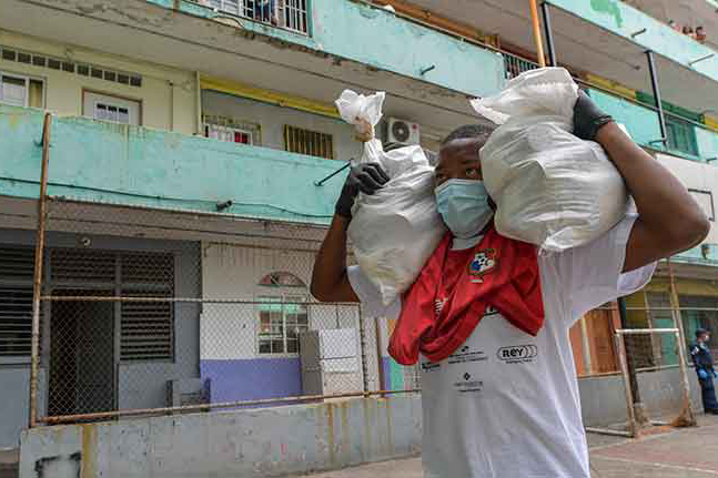 man with face mask carrying bags on both shoulders