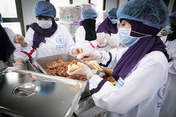 Women in protective gear preparing lunch.