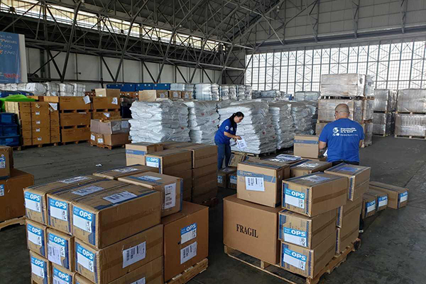 WHO workers sort through supplies in a warehouse.