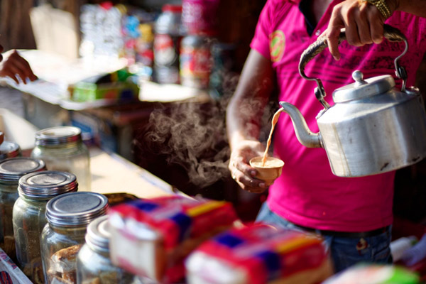 Steaming tea being poured from a metal tea kettle. 