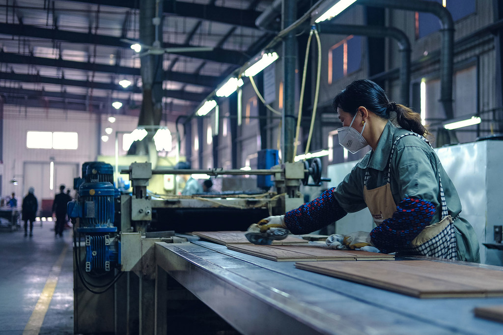 A worker cleans finished wood flooring in a factory in Zhejiang, China.