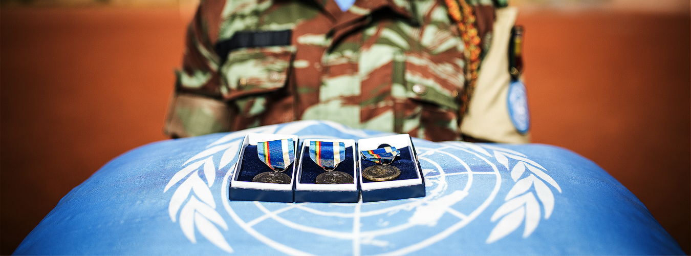 Trois médailles posées sur un coussin bleu avec le logo de l'ONU