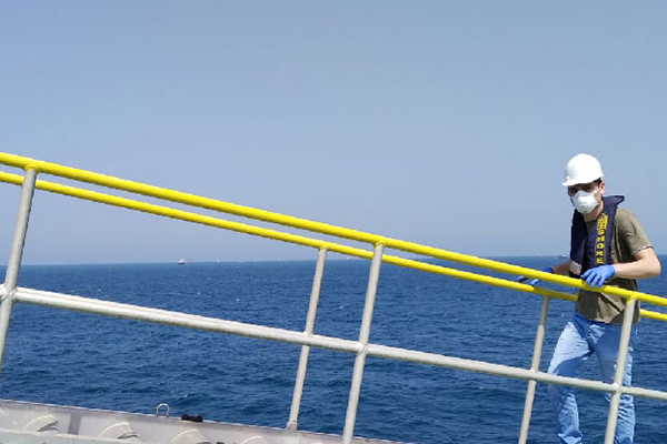 Man wearing a mask in front on a ship boarding ramp.