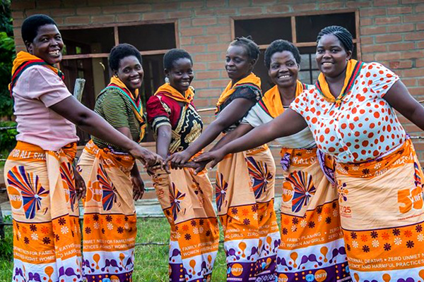 A group of women huddle and put their hands together. 