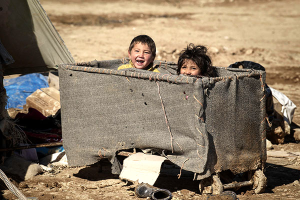 Two children inside a rolling cart smiling.