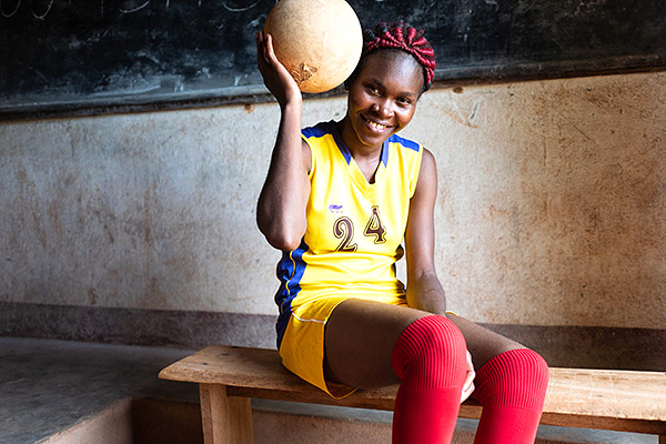 Girl in a futbol uniform holds a ball