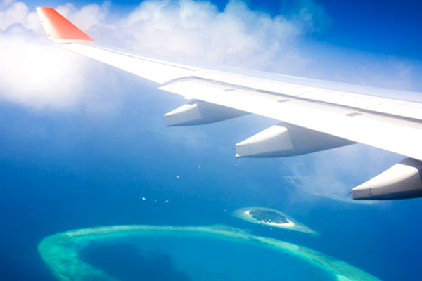 Airplane wing over blue seas.